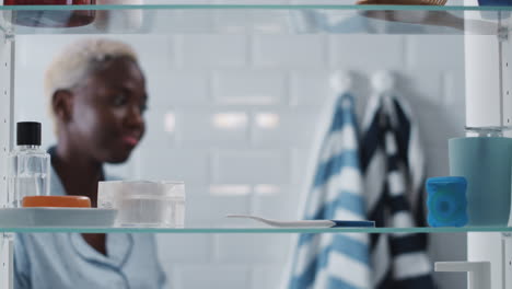 view through bathroom cabinet of anxious woman waiting for home pregnancy test result