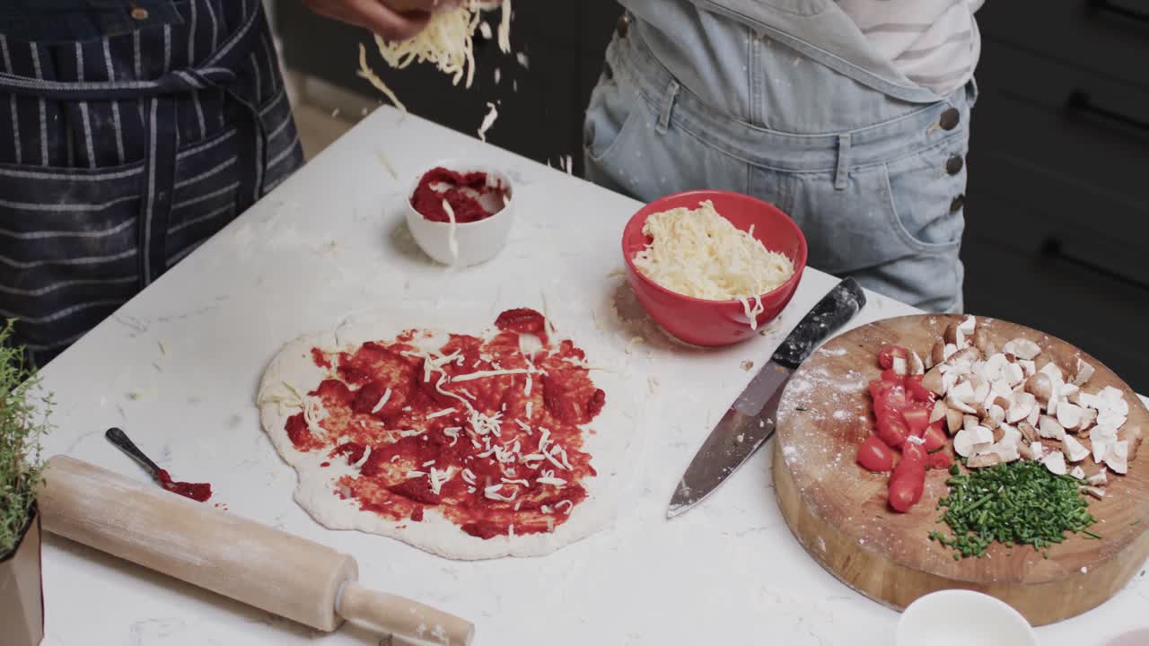 Inquadratura a mezzo busto di diverse amiche adolescenti che preparano la base della pizza al rallentatore.