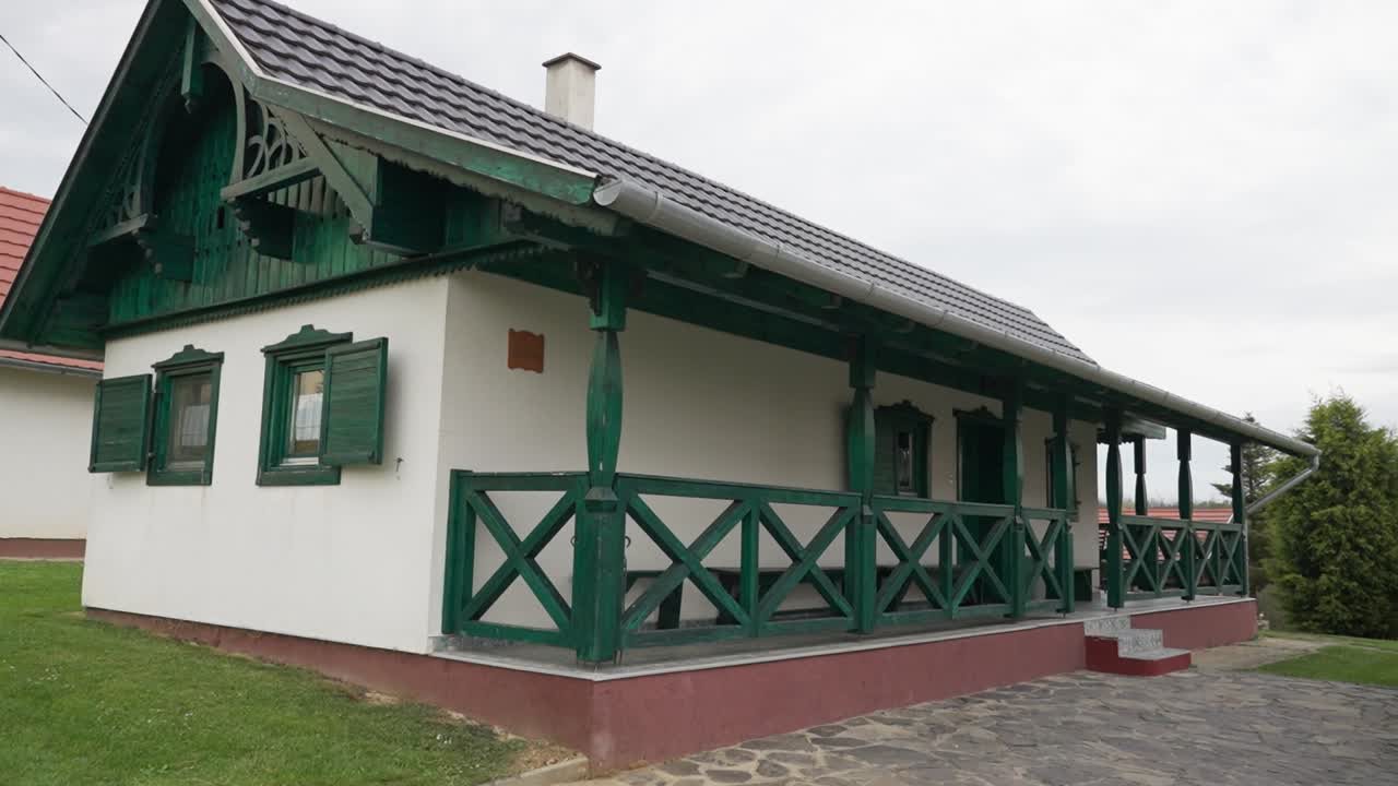 Close-up of a traditional cottage with green wooden veranda and shutters