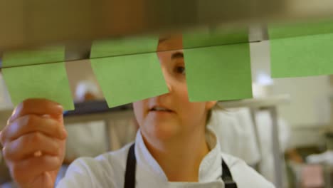 chef femenino chequeando el pedido en la cocina 4k