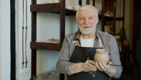 senior potter displaying handcrafted clay pot