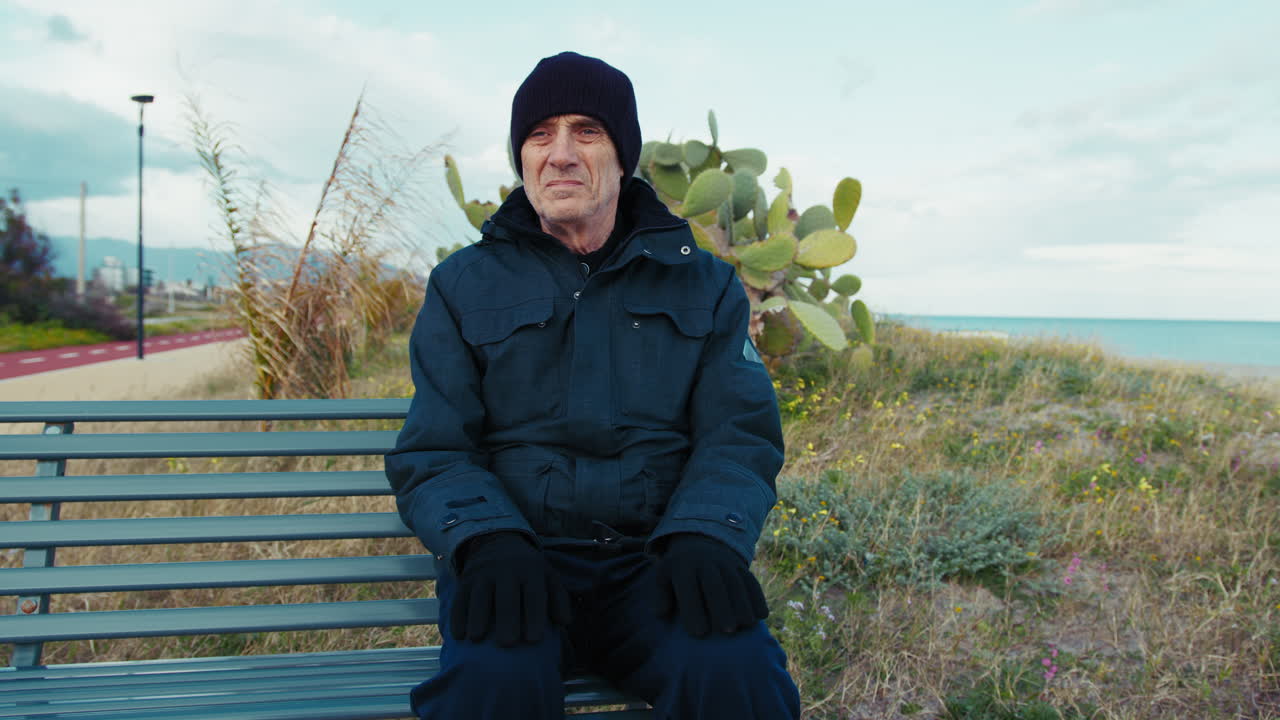 Senior Man Feeling Bored in Winter Sitting on a Bench by the Coast