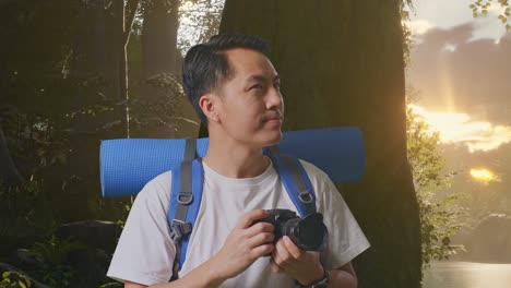 close up de un excursionista masculino asiático con una mochila de montañismo sosteniendo una cámara en sus manos y luego mirando a su alrededor mientras explora la naturaleza del bosque