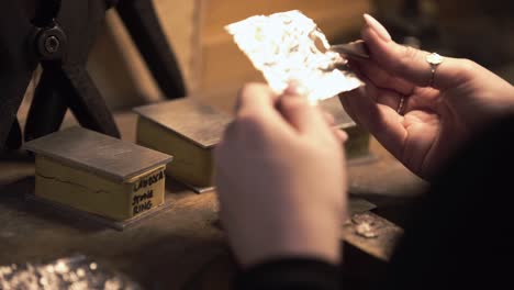 Shot-of-a-female-jeweller-making-an-impression-on-silver-metal-using-the-flame-from-a-candle