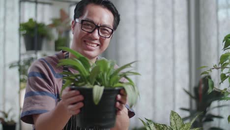 smiling man holding a potted plant