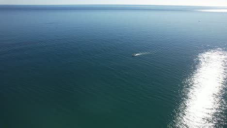 Luftaufnahme-über-Dem-Kopf,-Während-Sich-Ein-Kleines-Grünes-Boot-Auf-Den-Weg-Zum-Meer-Macht