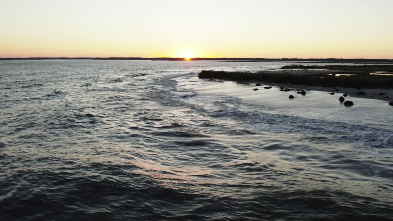 Orbita aerea bassa che si alza sopra le onde dell'oceano che si infrangono sulle rive al tramonto, Isola di Chincoteague Virginia, slow motion
