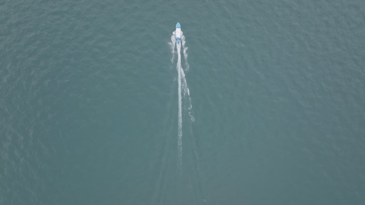 과테말라의 아티틀란 호수에서 해안으로 향하는 쾌속정을 따라잡고 날아가는 넓은 항공 영상