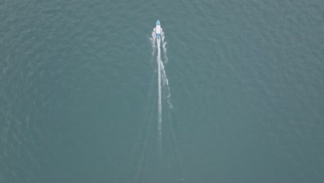 wide aerial footage catching up to and flying over a speedboat heading towards the shore on lake atitlan in guatemala
