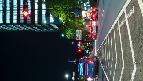 Timelapse-De-Una-Concurrida-Calle-Nocturna-Con-Mucho-Tráfico-De-Automóviles-En-El-Distrito-De-Yongsan-De-Seúl-En-El-Semáforo---ángulo-Bajo,-Vista-De-La-Torre-Namsan-Iluminada---Vertical