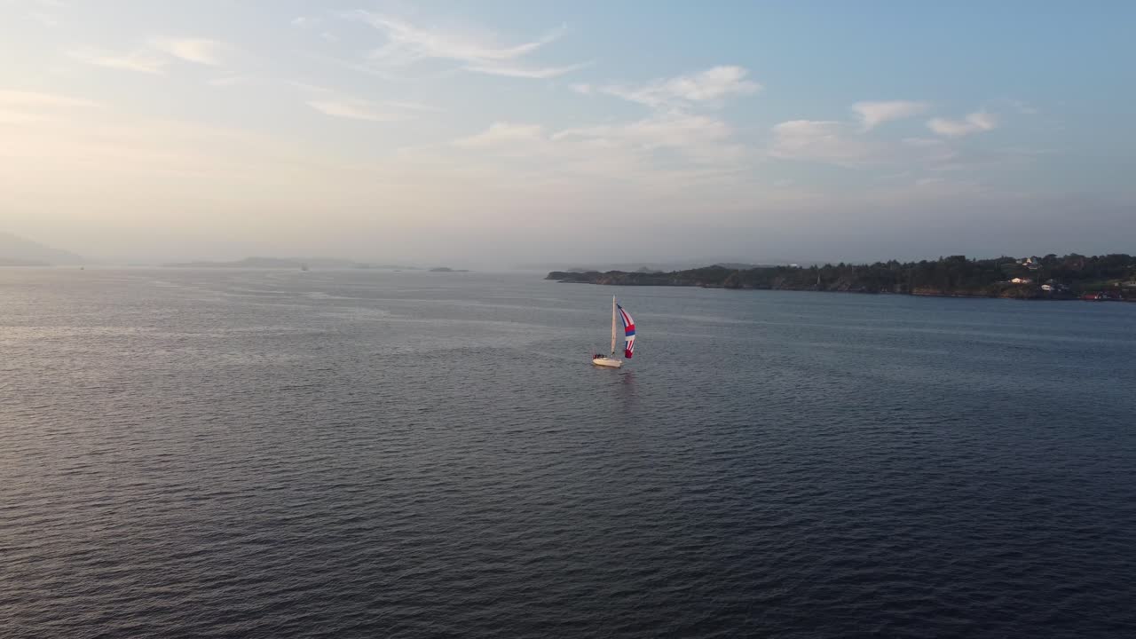 Private sailing boat heading for open seas during sunset - Golden light in beautiful calm evening - Norway aerial