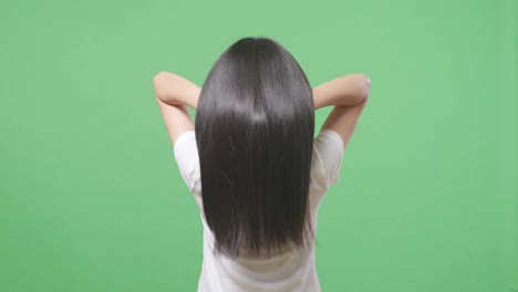 back view of a woman fluttering her long black and blond straight healthy hair in the green screen background studio