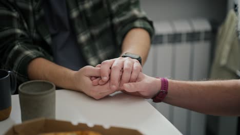 and two middle-aged men hold hands during their difficult communication and their relationship in the kitchen in a modern apartment. relationships and mutual understanding during a difficult conversation about relationships in an lgbt couple of two men