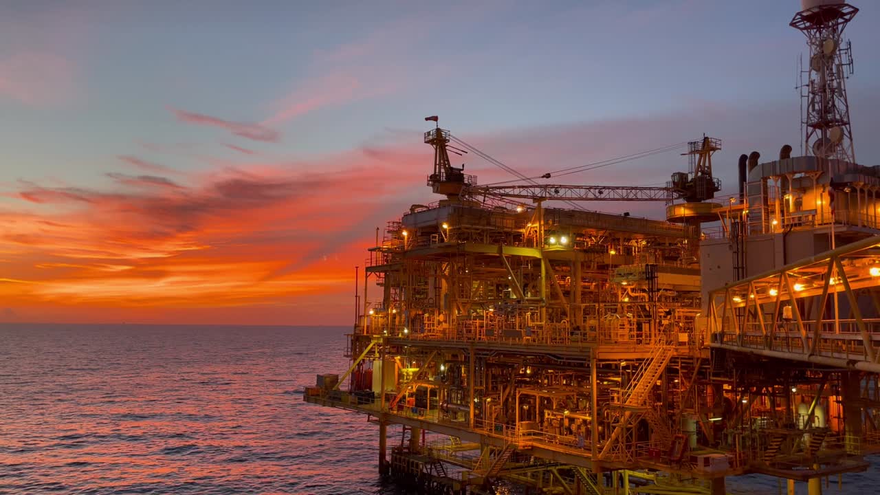offshore oil and gas platform in sunset time the platform produced raw gases and crude oil for sent to onshore refinery, petrochemical plant and tanker for export for industry concept.