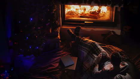 nice evening by the fireplace and new year tree a man admires the fire in the fireplace