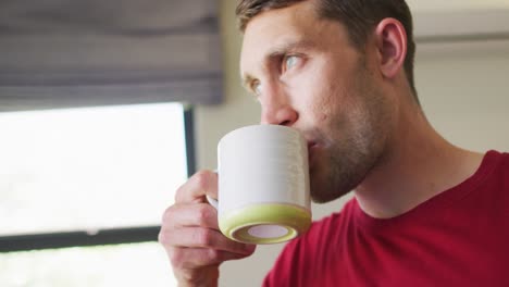 Un-Hombre-Caucásico-Pensativo-Está-Mirando-Por-La-Ventana-Y-Tomando-Café