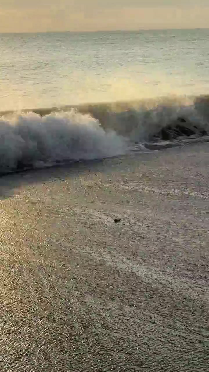 Onde oceaniche che si infrangono su una spiaggia sabbiosa all'ora d'oro
