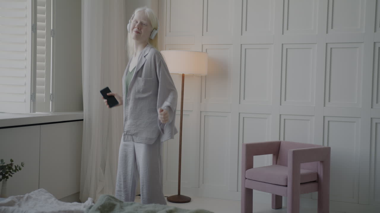 Woman Dancing in Pajamas with Headphones and Smartphone