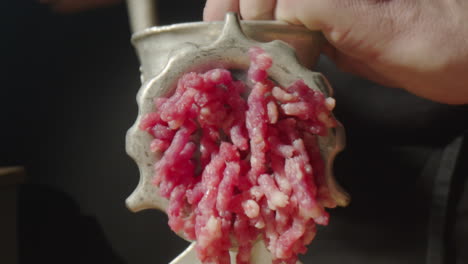 chef using meat grinder for making ground beef