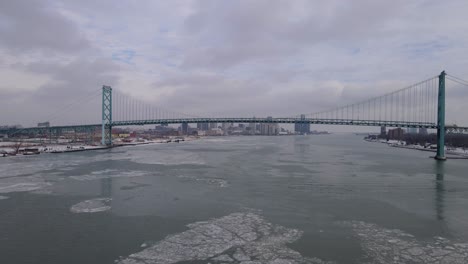 -Ambassador-Bridge-connecting-two-countries-over-icy-Detroit-river,-aerial-view
