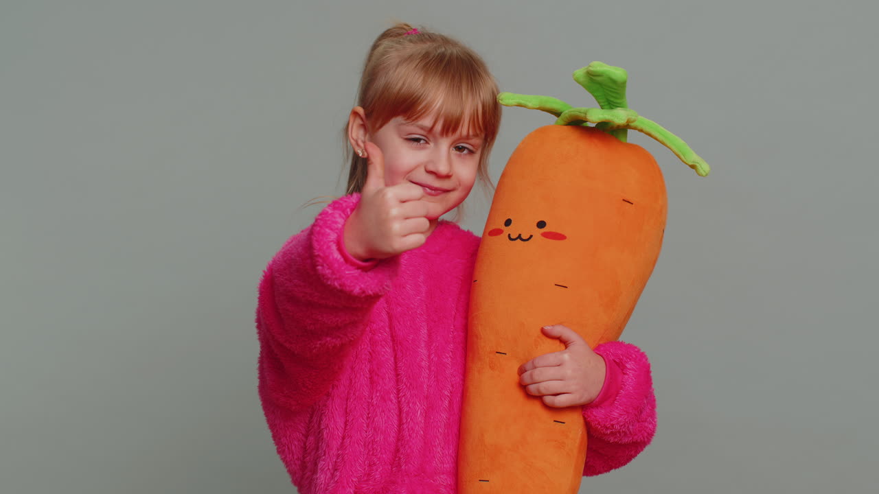 행복 한 십대 전 아이 소녀 아이 는 긍정적 인 표지판 처럼 엄지 손가락 을 올려 놓고 카메라 를 긍정적 으로 바라보고 있다