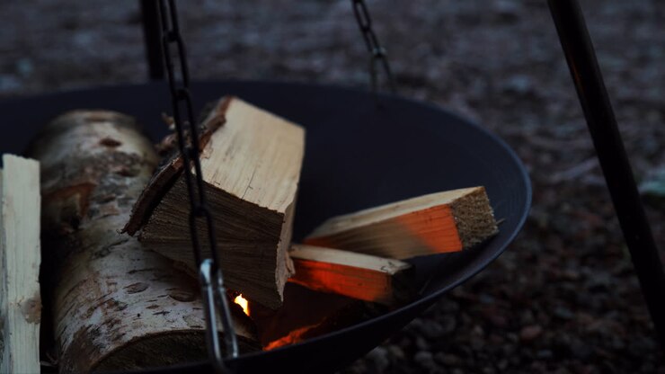 Camping fire wood on metal plate, slowly burning and being started