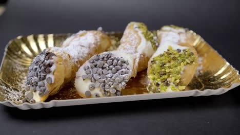 tilt down shot of typical sicilian cannoli with cream plus chocolate and pistachio grannella