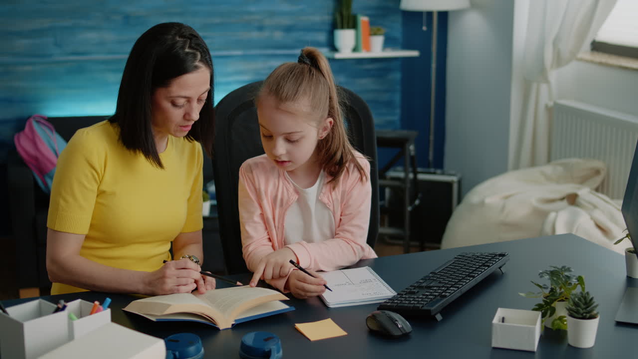 Parent using books to help little girl with homework at desk