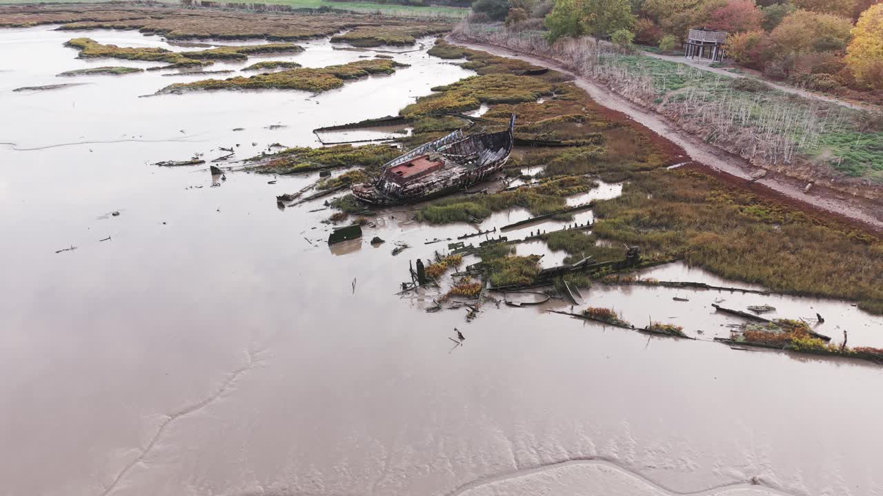 Essex mudflat damaged shipwreck stuck in low tide salt marsh aerial view on Blackwater river