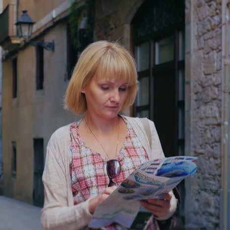 Eine-Frau-Mit-Einer-Karte-In-Der-Hand-Geht-Durch-Die-Engen-Straßen-Des-Gotischen-Viertels-In-Barcelona