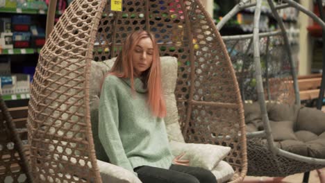 woman choosing, sitting in a hanging chair in hardware store