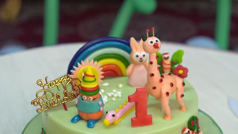 close-up cinematic shot of a one year old kid's birthday party celebration with animals, rainbow on the top of the cake