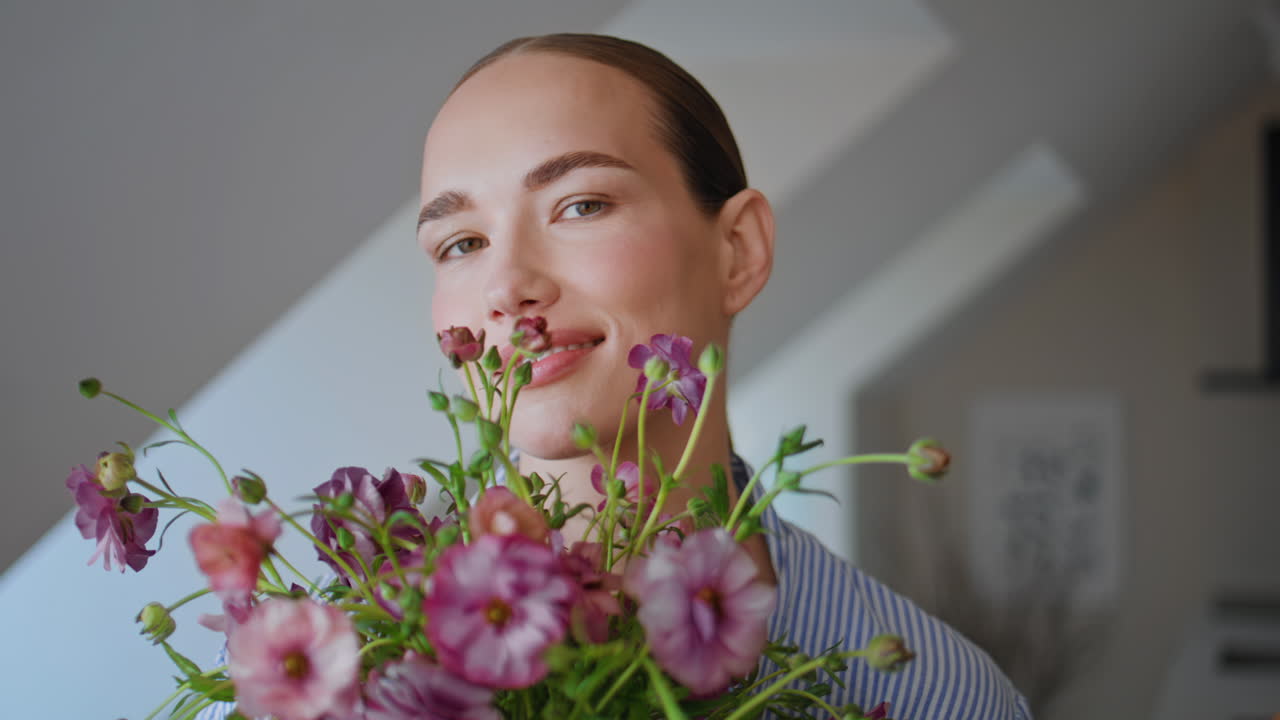 Young lady inhaling daisies fragrance light flat closeup. Woman looking camera