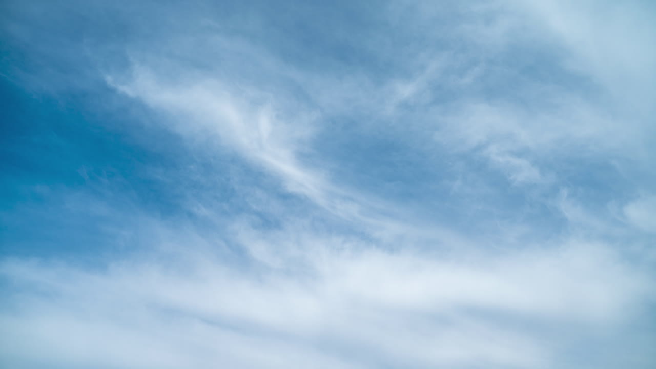 White cirrus clouds move against background of blue sky. Summer timelapse. Gradual closing of sky with clouds. Change of weather