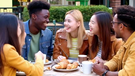 group of multiethnic friends having breakfast together outdoors.