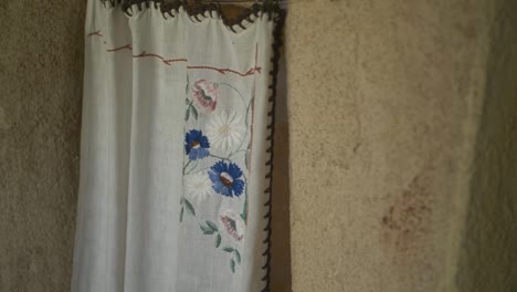 Old-curtain-with-knitted-flower-ornaments-on-abandoned-house-in-remote-village