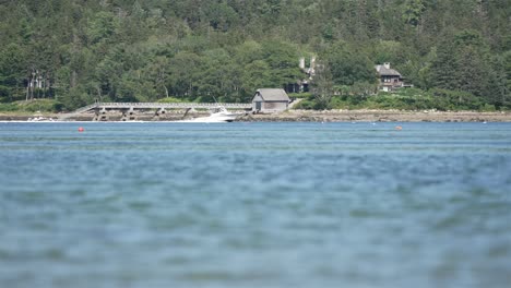 la lancha rápida conduce rápidamente a través del tranquilo lago plácido en cámara lenta, la ladera boscosa detrás