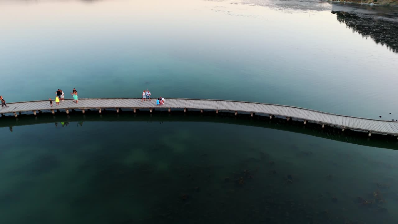 구부러진 보드워크는 황혼에 평온한 물 위에 확장되어 조용하고 조용한 장면을 만니다.