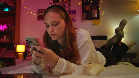 a young woman using her phone in bed at night