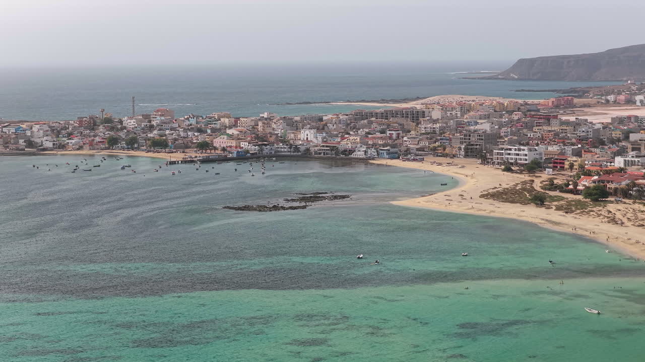 Sal Rei şehrinin havadan görünümü: Birçok renkli evin bulunduğu Eski Şehir, küçük liman, turkuaz okyanus ve kumlu plaj, arka planda çöl. Boa Vista, Yeşil Burun Adaları.