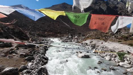 colorful buddhist prayer flags flutter in the wind on a suspension bridge spanning a rushing river in the himalayas, creating a mesmerizing display of vibrant colors and spiritual symbolism