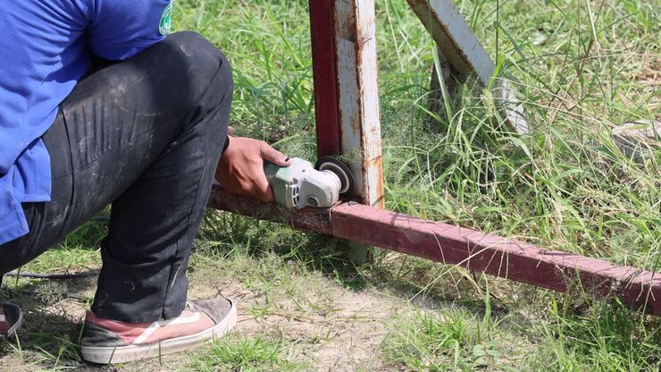 Worker safely using angle grinder outdoors.