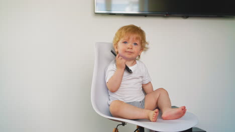 Un-Niño-Rubio-Se-Sienta-En-Una-Silla-Blanca