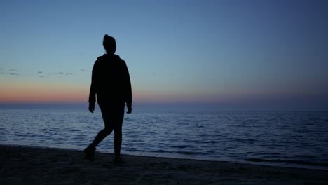 mujer yogui desconocida practicando ejercicios de relajación en la playa hermosa noche.