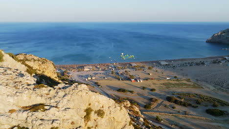 Aerial view revealing the Tsambika Beach behind a rocky cliff, sunset in Rhodes