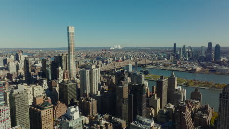 Aerial-descending-footage-of-apartment-buildings-in-city-and-long-Queensboro-Bridge-over-East-River.-Manhattan,-New-York-City,-USA