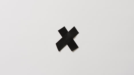 video of close up of black tape forming cross on white background