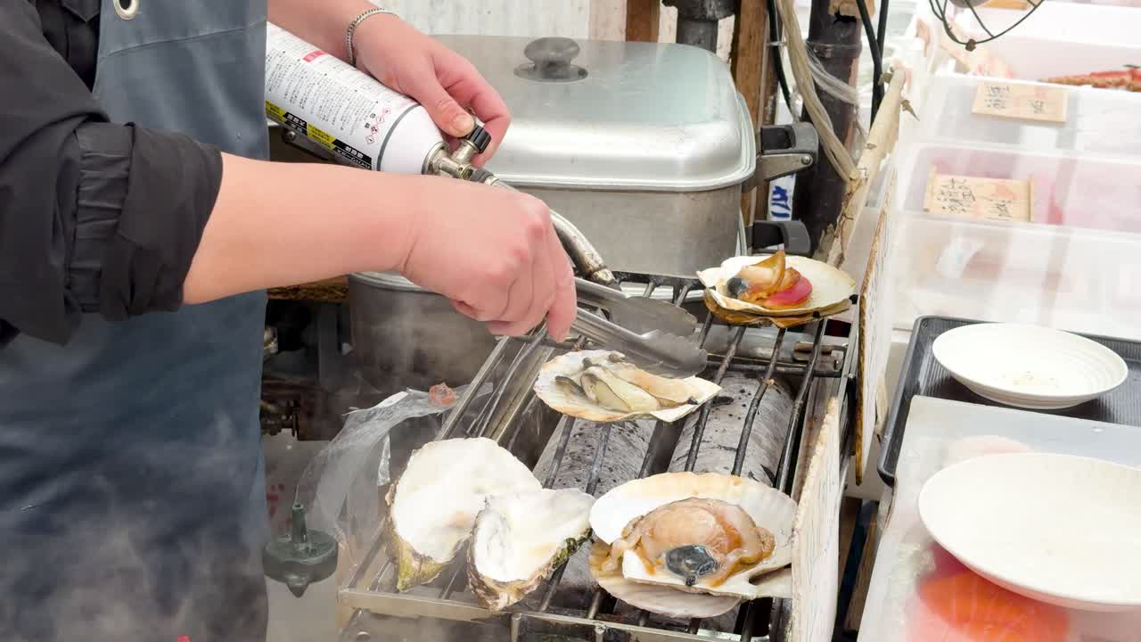 Close-up of a chef using a blowtorch to sear fresh shellfish on a grill