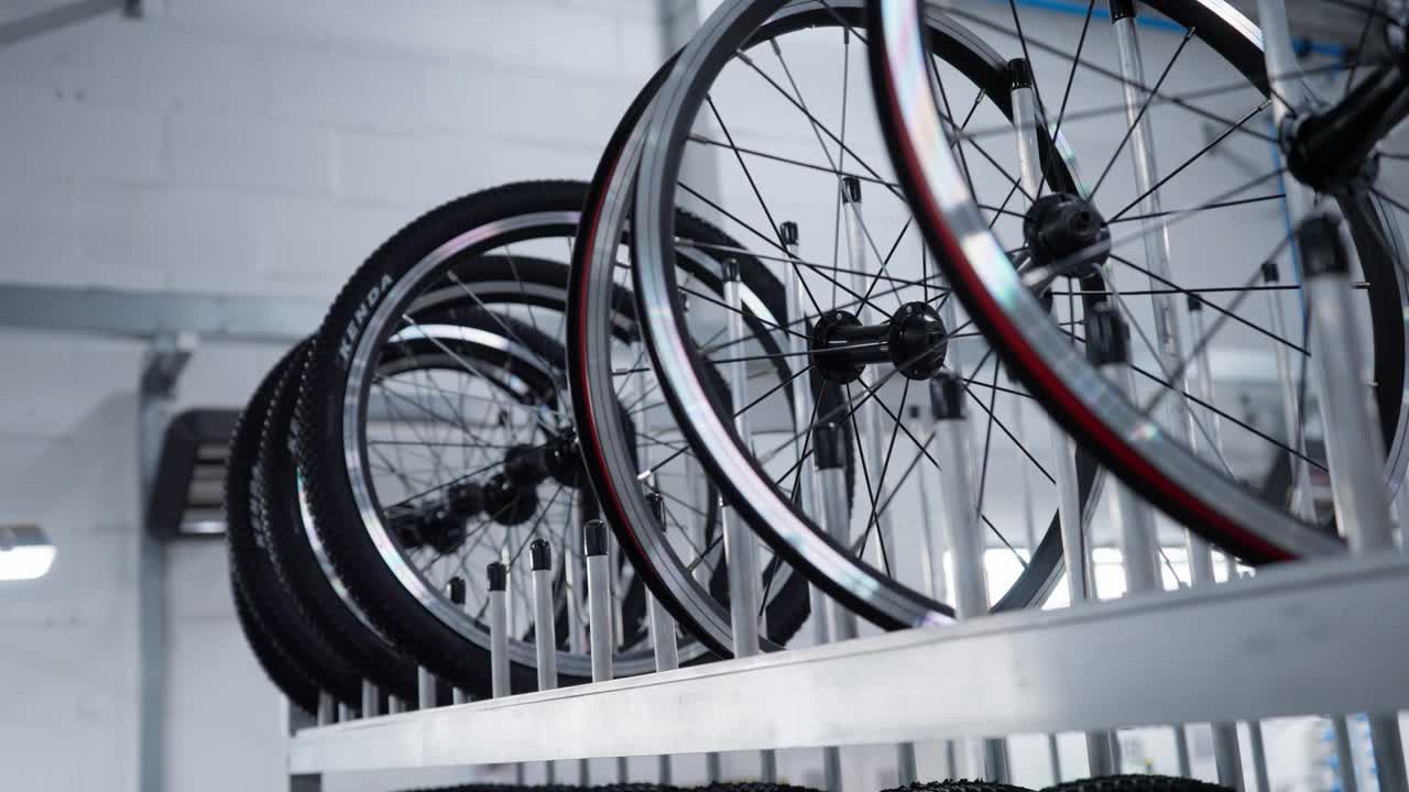 Roda alinhada em fábrica de bicicletas. Homem coloca roda nova no suporte.