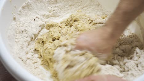 manos amassando masa de bejgli en un cuenco grande para la preparación de pasteles de navidad